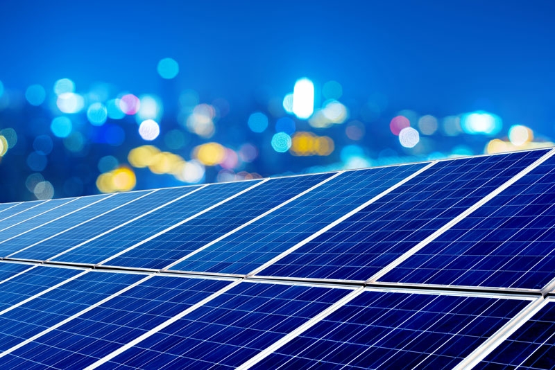 Solar panels with the night sky and lights in the background