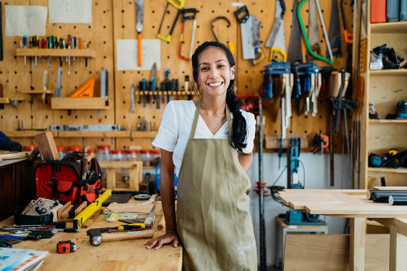 a woman stands in a shop in front of a wall full of tools